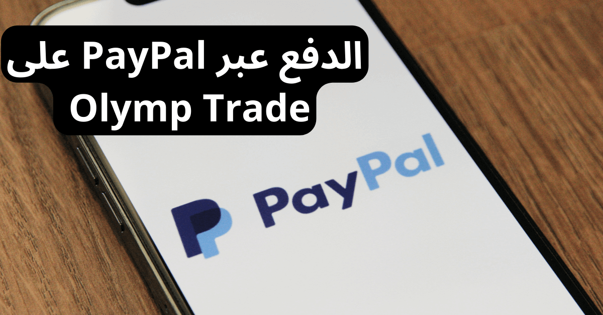 الدفع عبر olymptrade paypal أمامها هاتف ذكي على شاشته يظهر شعار تطبيق PayPal و خلفية بيضاء هذا الهاتف فوق طاولة خشبية